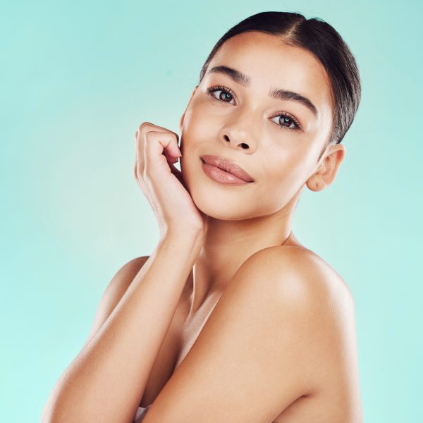 Closeup face beautiful young mixed race woman. An attractive female posing in studio isolated against a blue background. A skincare regime that keeps your skin soft, smooth, glowing and healthy