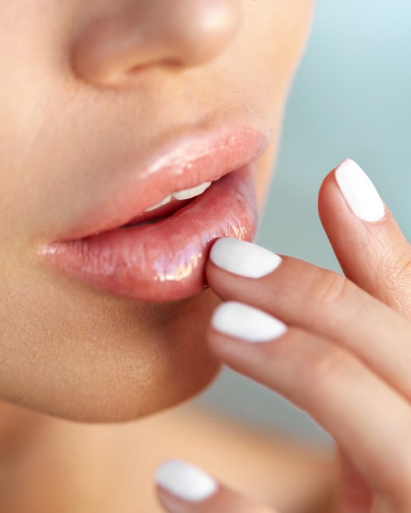 Lip Protection. Closeup of Beautiful Young Woman Healthy Lips. Female Model Mouth With Smooth Perfect Skin And Natural Manicure Touching Her Plush Lips. Lip Care And Beauty. High Resolution